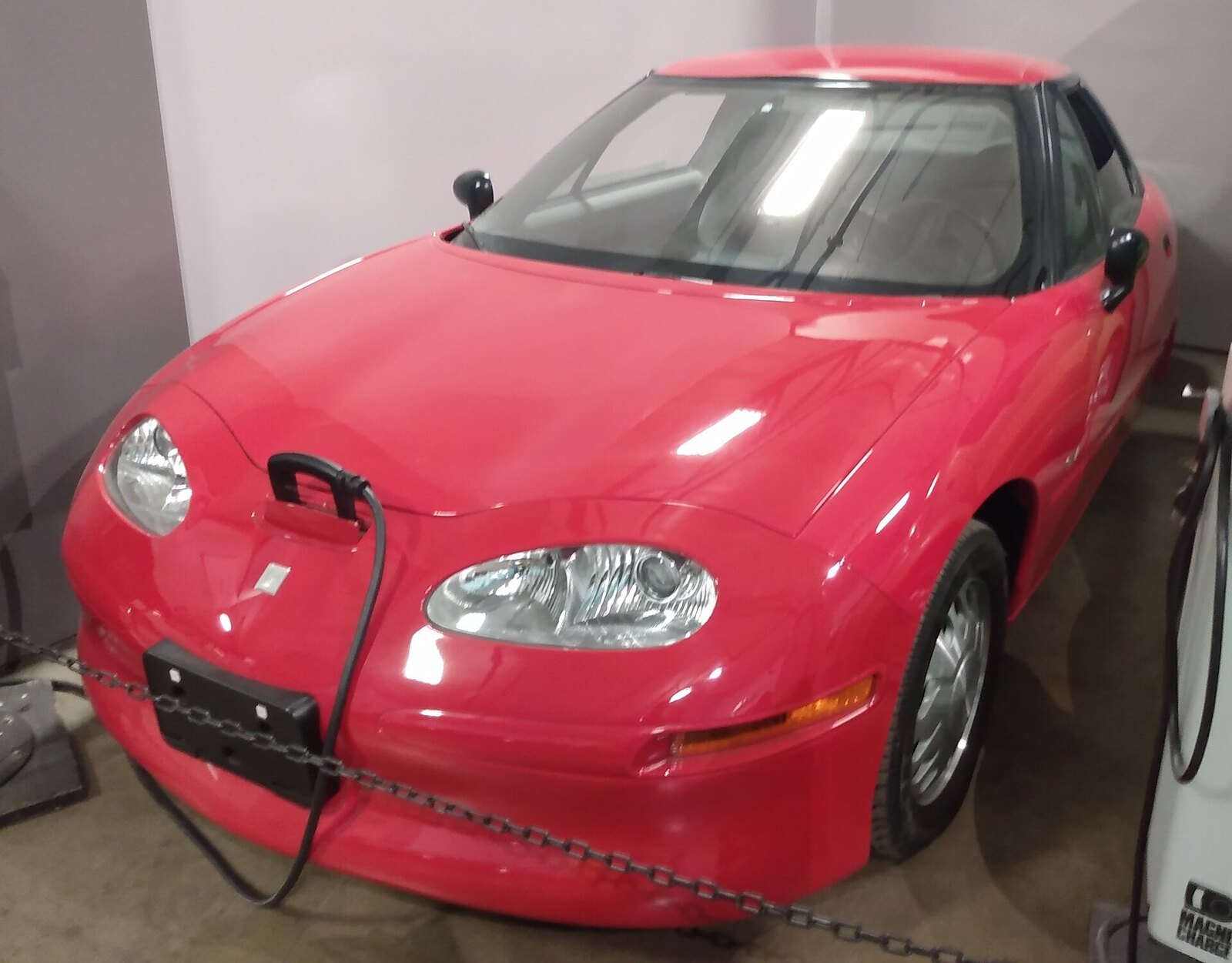 Red 1997 General Motors EV1 electric car plugged in and charging