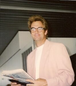 Huey Lewis around 1990 in a pink blazer, signing autographs at O'Hare airport