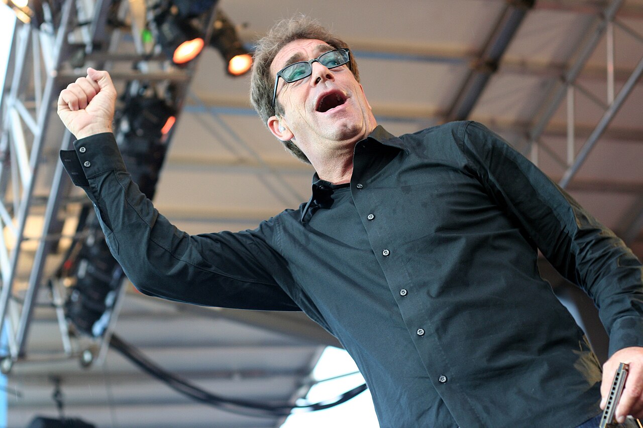 Huey Lewis performing live on stage in 2013, fist raised