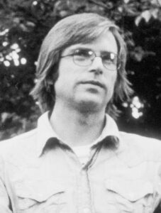 Sam Neill as a young long haired actor in glasses, in a black and white still from the 1974 New Zealand film Landfall